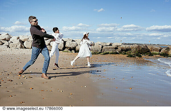 mixed race family hvaing a stone throwing competition at the beach