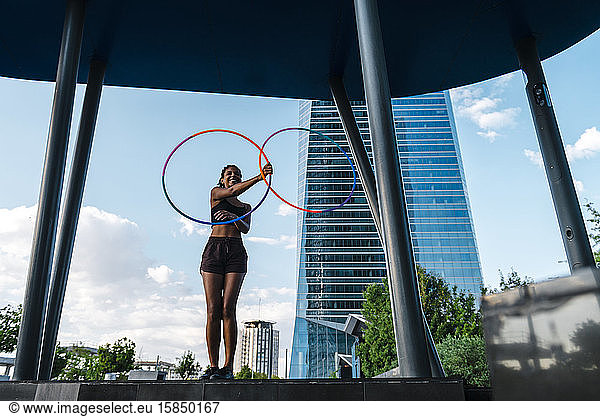 Mixed race generation Z woman performing Hula Hoop dance in downtown
