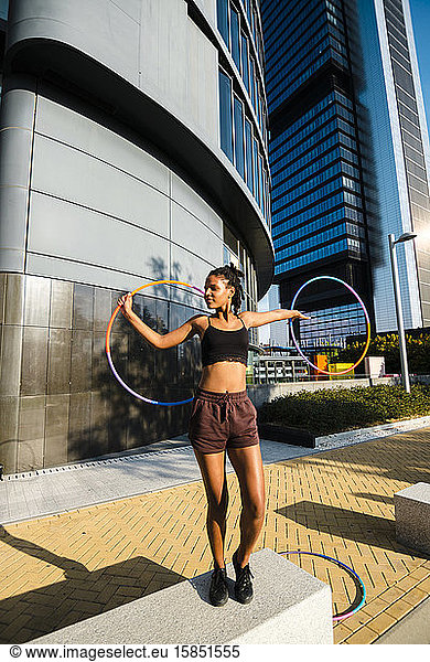 Mixed race generation Z woman performing Hula Hoop dance in downtown