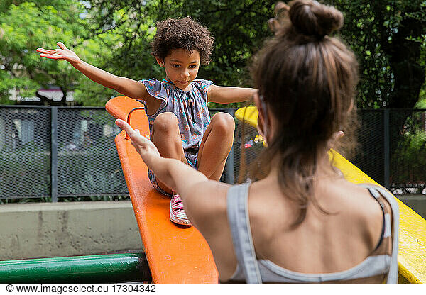 Mixed race girl enjoying her mom at playground outside