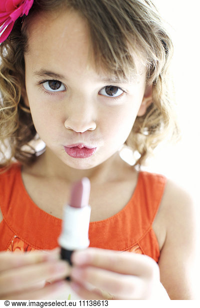 Mixed race girl playing with lipstick