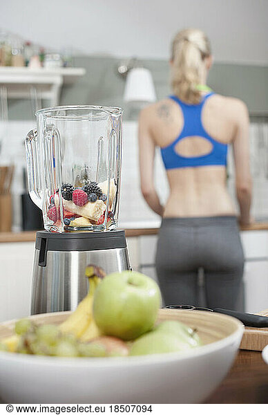 Mixer with fruits in the kitchen with young woman in the background  Bavaria  Germany