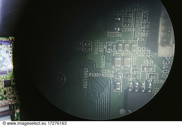 Mobile circuit board seen through magnifying glass at repair shop