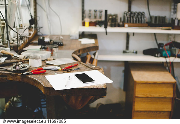 Mobile phone and document on workbench in jewelry workshop
