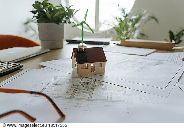 Model house on blueprint at desk