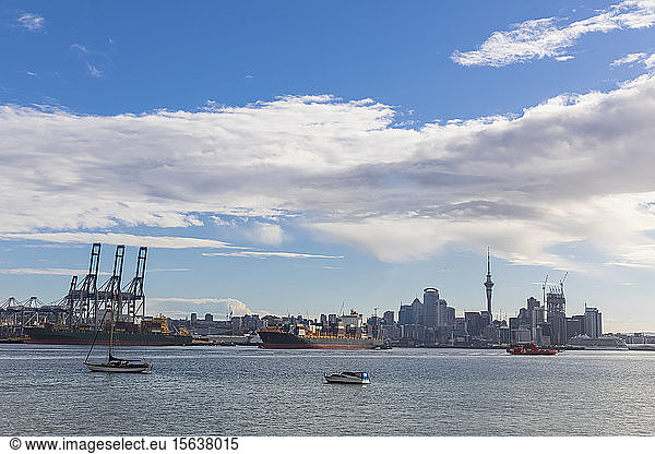 Modern buildings and Devonport by sea against cloudy sky in Auckland  New Zealand