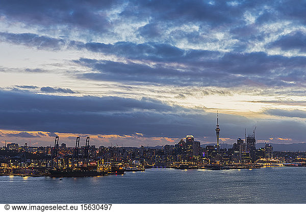 Modern buildings by sea against cloudy sky at dusk in Auckland  New Zealand