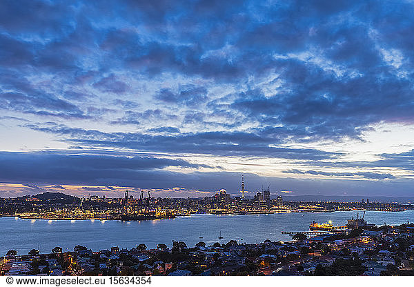 Modern buildings by sea against cloudy sky at dusk in Auckland  New Zealand