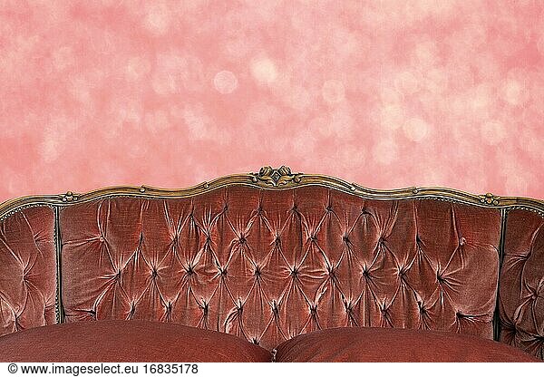 Modern classic pink sofa with pink bokeh wall pattern luxury retro interior design copy space or space for text background close up.