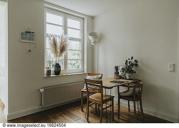 Modern interior of room with table and chairs by window at old house
