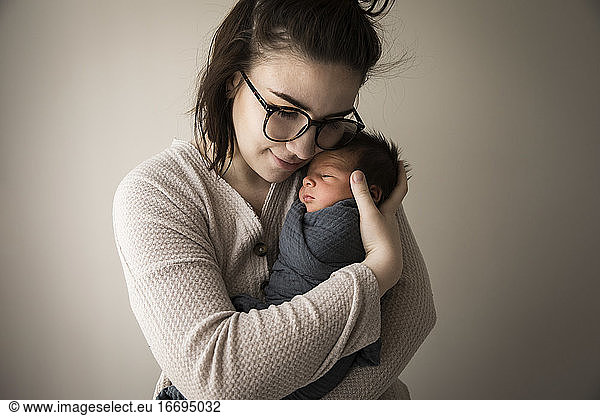 Modern Millennial Hipster Mom Snuggles Swaddled Newborn Baby Son