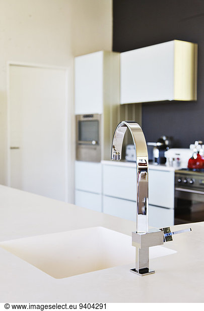 Modern stainless steel faucet and white kitchen sink in clean kitchen
