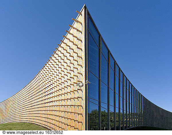 Modern university buildings  wooden beams projecting from a curved wood cladding wall  on a curved ground surface