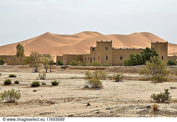 Moderne Hausburg (Kasbah) vor Sanddüne in Wüste Wüstenwohnort burgähnliches Haus in der Wüste Merzouga Marokko Afrika