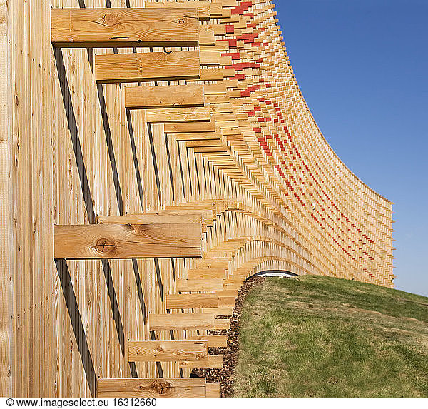 Moderne Universitätsgebäude  Holzbalken  die aus einer gebogenen Holzverkleidungswand herausragen  auf einer gekrümmten Grundfläche