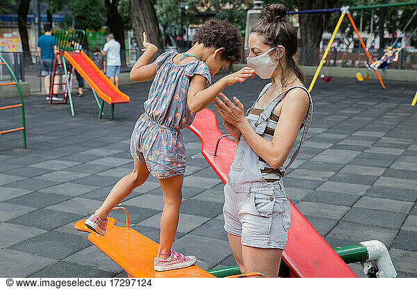 Mom and daughter enjoying at playground outside in a new normal life.
