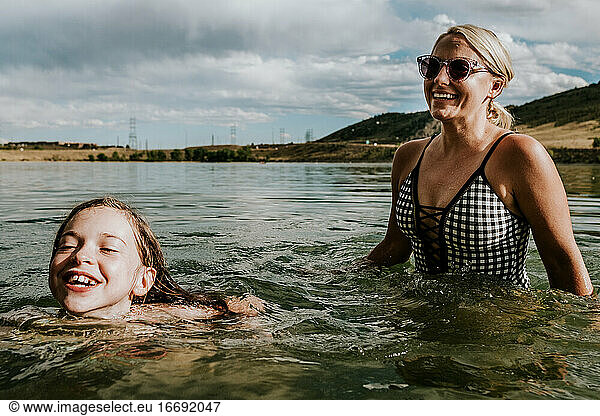 Mom and daughter happily playing in a lake on a summer day