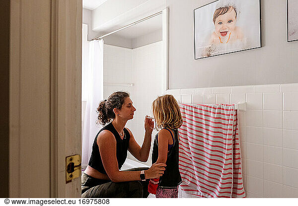 mom and daughter in bathroom taking temperature with thermometer