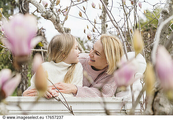 Mom and daughter in the park with a blooming magnolia.