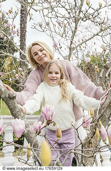 Mom and daughter in the park with a blooming magnolia.