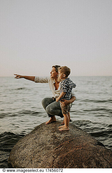 mom and son sitting on the stone in the sea