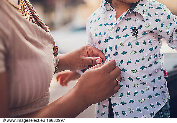 Mom buttoning baby boy's shirt  close up to hands