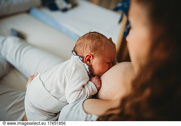 Mom holding cute newborn baby breastfeeding at home