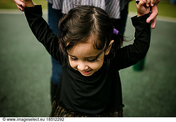 Mom holding daughter's hands while standing at park