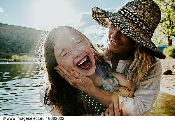 Mom holding young happy daughter while daughter laughs