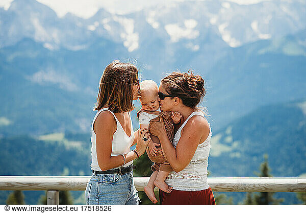 Moms kissing baby boy in the German Alps mountains in summer