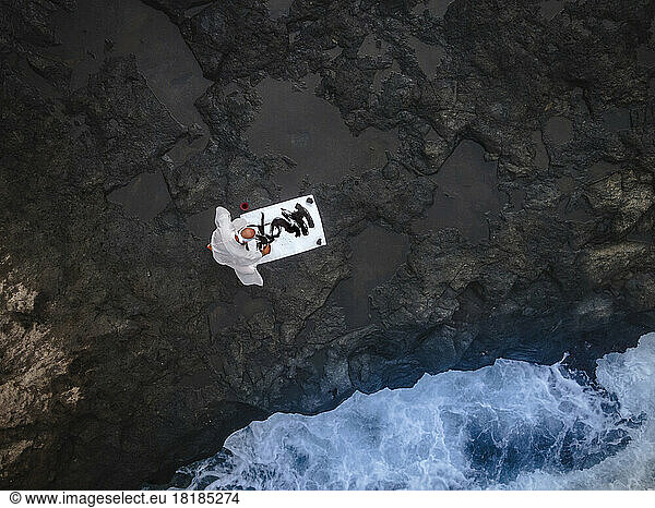 Monk doing calligraphy sitting on rock by sea