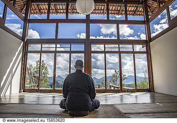 Monk meditating in a Japanese style house among the mountains