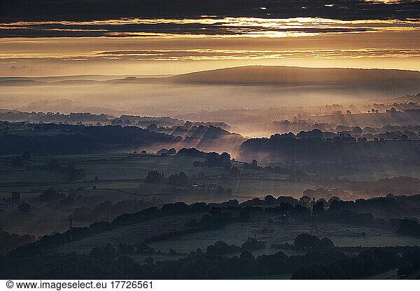 Morning sunbeams and early morning fog cover the Cheshire Plain at sunrise  from Bosley Cloud  Cheshire  England  United Kingdom  Europe