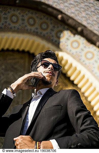 Moroccan man with sunglasses and suit using smart phone together