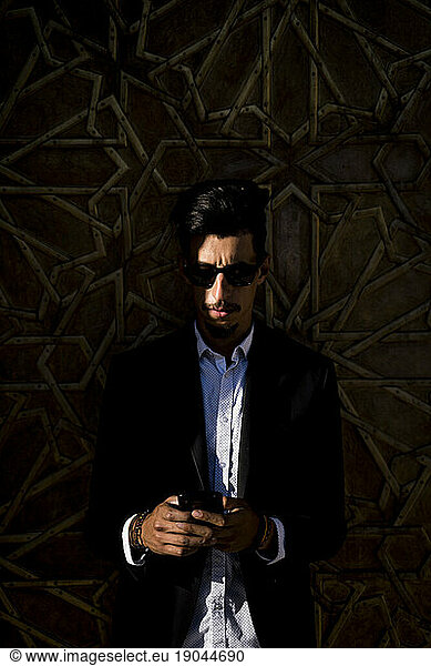 Moroccan man with sunglasses and suit using smart phone together