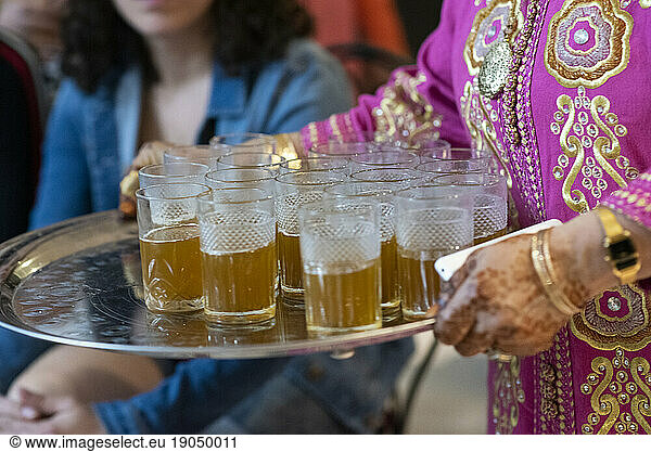 Moroccan woman carrying a tray with tea for the guests of a party.