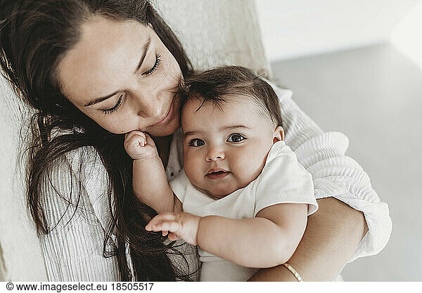 Mother and baby daughter cuddling in hammock in natural light studio
