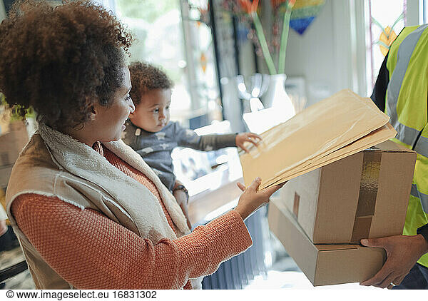 Mother and baby daughter receiving package from delivery person