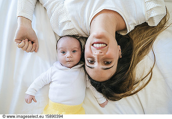 Mother and baby lying in bed looking at camera