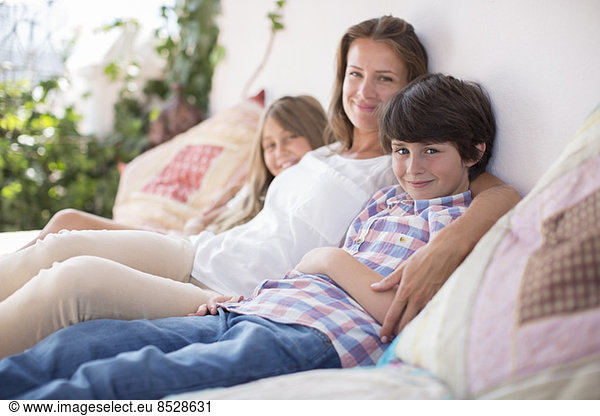 Mother and children relaxing on patio sofa