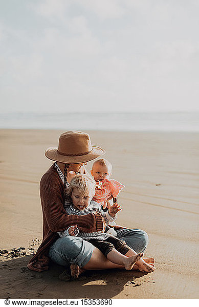 Mother and children sitting on beach