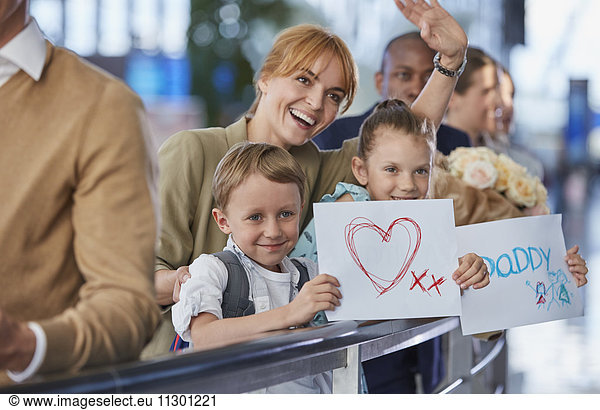 Mother and children with welcome signs for father at airport