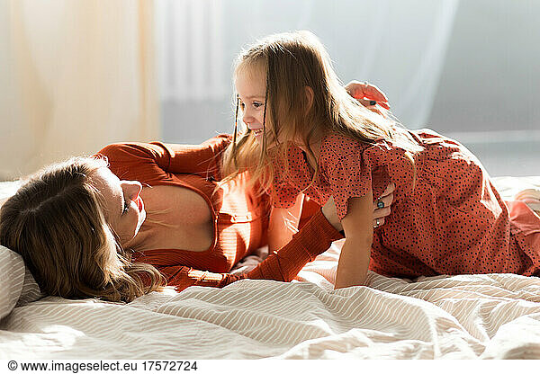 Mother and daugher wallowing in bed at home and laughing