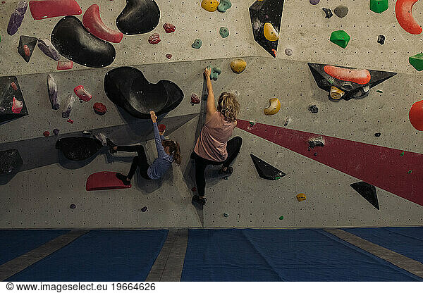 mother and daughter boulder climbing indoors together