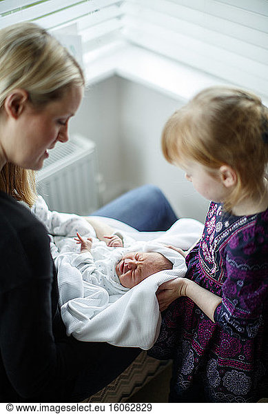 Mother and daughter caring for newborn baby