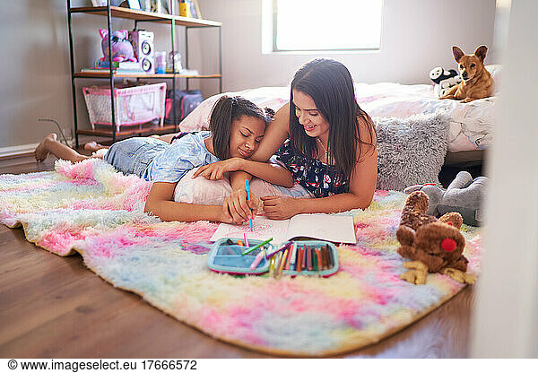Mother and daughter drawing on bedroom rug