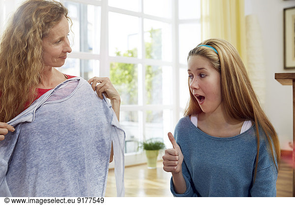 Mother and daughter fitting clothes at home