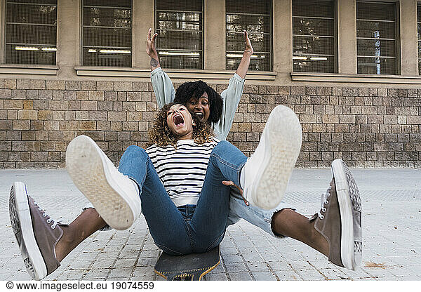 Mother and daughter having fun together sitting on skateboard