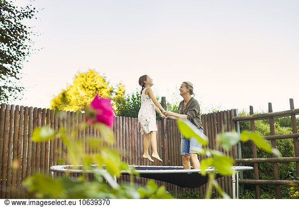 Mother and daughter jumping on trampoline in garden