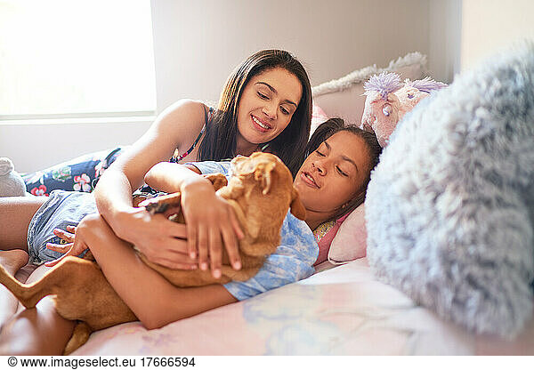 Mother and daughter laying in bed with dog at home
